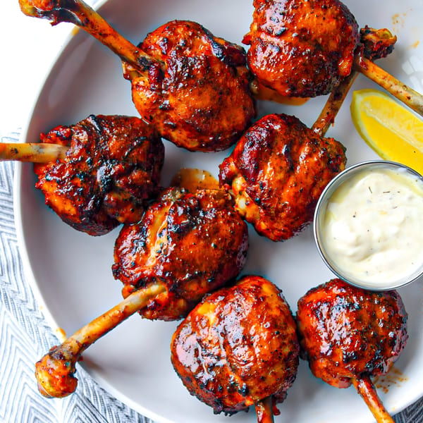 Himalayan Grill's Indian chicken lollipops with a side of dipping sauce and lemon wedges.