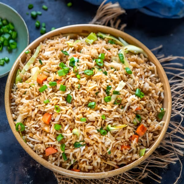 Himalayan Grill's vegetable fried rice with carrots, cabbage, and green onions in a wooden bowl.