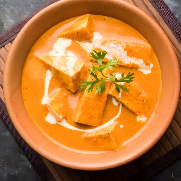 Himalayan Grill's paneer butter masala, an Indian dish with paneer cubes in a creamy orange sauce, garnished with cilantro.